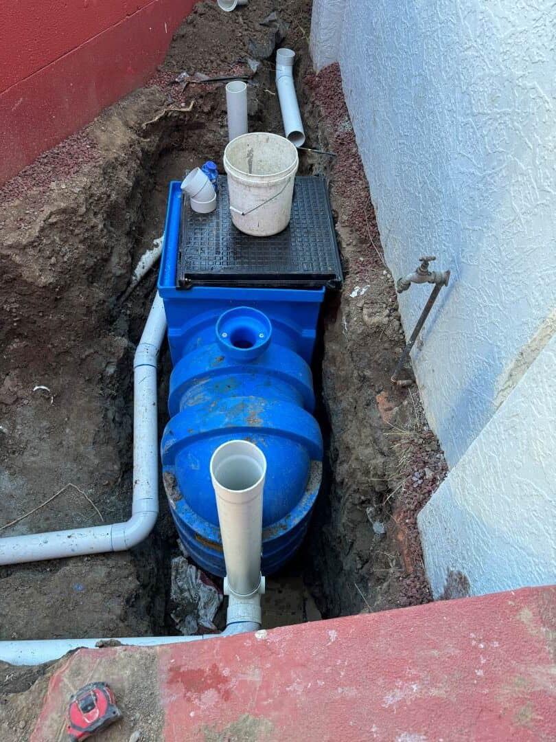 blue plastic tanks in a hole with white PVC pipes